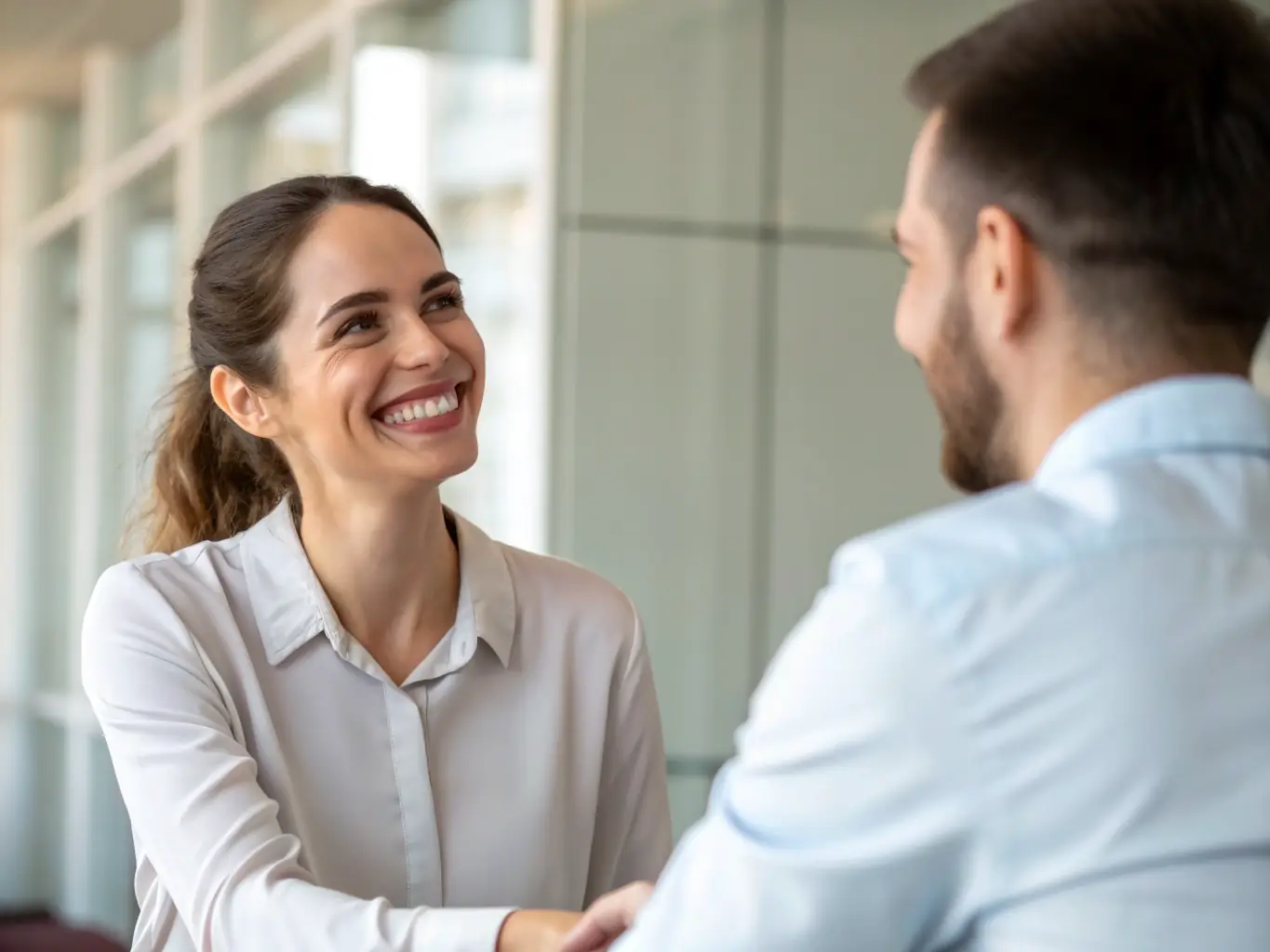 A businesswoman confidently shaking hands with a tax advisor, symbolizing a trustworthy and reliable partnership in a modern office environment.
